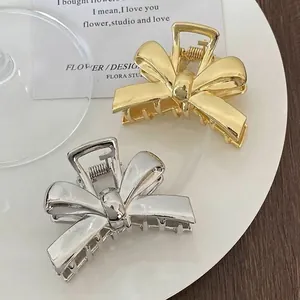 Elegant gold and silver alloy bow hair clips on a white plate with minimalist design