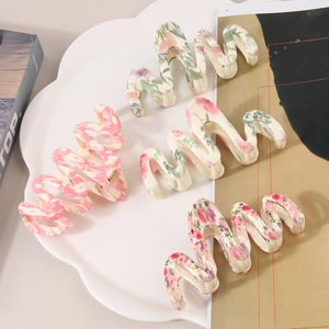 Lot de quatre pinces à cheveux à motif floral ondulé disposées sur un plateau décoratif