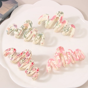 Lot de quatre pinces à cheveux ondulées avec motifs floraux sur une assiette blanche