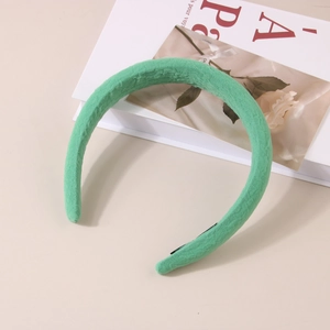 Vue détaillée du serre-tête en tissu texturé vert avec design plissé et rembourrage