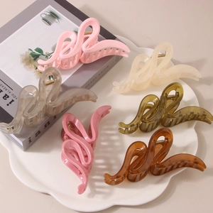 Détail de 6 pinces à cheveux colorées au design ondulé sur une assiette décorative blanche