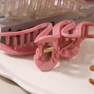 Pinces à cheveux macaron rose et champagne irrégulières présentées sur une plaque céramique