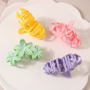 Detail view of four colorful floral hair claws in pastel tones on a white petal tray