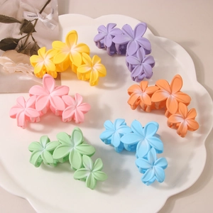 Detailed set of six colorful matte frangipani flower hair claws with soft gradient colors