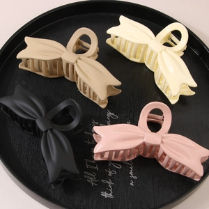 Dettaglio di fermagli per capelli opachi a forma di fiocco in beige, giallo, nero e rosa
