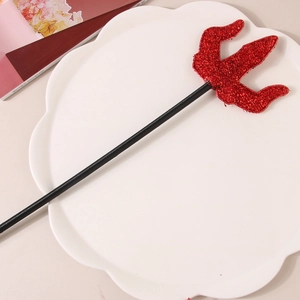 Glittery red devil trident wand accessory for Halloween costumes on a white tray
