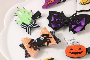 Detail of Halloween hair clips featuring sequins, bats, and pumpkins on a white tray
