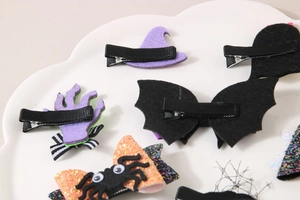 Detail view of Halloween hair clips showing bat, spider and witch hat motifs with clips