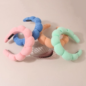 Detail view of four colorful thickened wavy handmade headbands on a glass shell tray