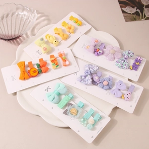 Buntes Stoff-Haarspangen-Set für Kinder mit Blumen- und Tierclips auf einer Keramikschale