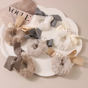 Plush houndstooth bow hair ties set with faux pearls on a stylish display tray