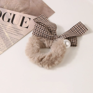 Detail of plush hair tie with houndstooth bow and pearl accent on a fashion magazine
