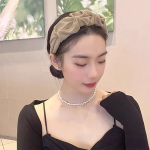 Primer plano de una diadema plisada caqui con diseño retorcido llevada por una modelo