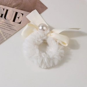 Detail of white plush faux fur scrunchie with cream ribbon bow and pearl accent