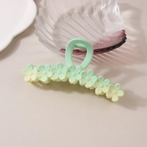 Detail of gradient flower hair claw clip with matte finish on minimalist white desk