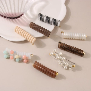 Close-up of spiral hair ties set with pearls and metallic ends in various elegant colors