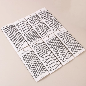 Close-up of black wavy metal hair clips with matte paint on white cardboard card packaging