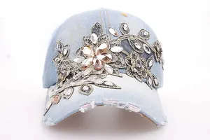 Detail of light blue denim baseball cap featuring 3D floral embroidery and sparkling rhinestones