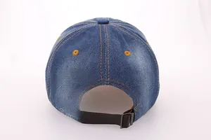 Detail of blue denim baseball cap featuring leather back strap and bronze metal buckle