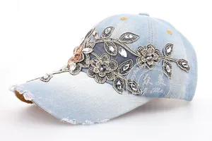Close-up of light blue denim baseball cap with grey lace floral patches and rhinestones
