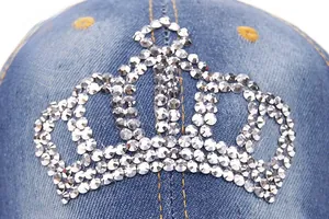 Detail of crown emblem with rhinestones on dark blue denim baseball cap surface