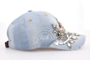 Close-up of light blue denim baseball cap featuring floral embroidery and sparkling rhinestones