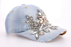 Close-up of light blue denim baseball cap with floral embroidery and rhinestones