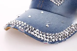 Close-up of crown rhinestone studs and distressed denim texture on a blue baseball cap