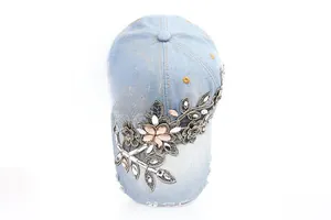 Detail of light blue denim baseball cap with floral embroidery and rhinestone accents