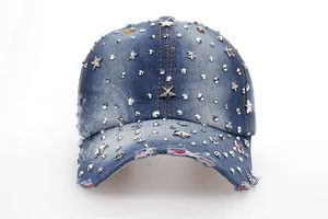Detail of silver star studs and vintage distressed edges on a blue denim baseball cap