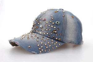 Détail d'une casquette en denim bleu clair vieilli avec strass dorés et pierres colorées