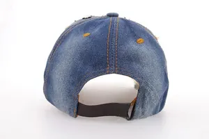 Detail view of denim baseball cap showing adjustable brown leather strap and metal buckle