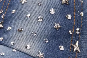 Detail of washed denim baseball cap with sparkling rhinestones and star metal studs