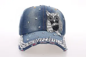 Detail of rhinestone owl patch and metal studs on distressed denim baseball cap