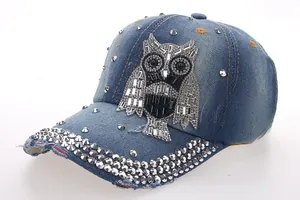 Close-up of sparkling rhinestone owl pattern and silver rivets on denim baseball cap