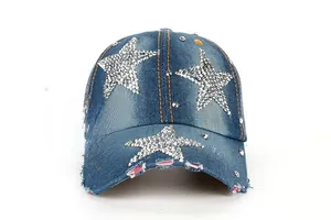 Détail d'une casquette en denim avec étoiles en strass, coutures orange et bord usé
