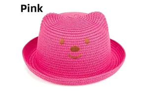 Détail d'un chapeau de paille tressé rouge rose pour enfants avec oreilles de chat et ours