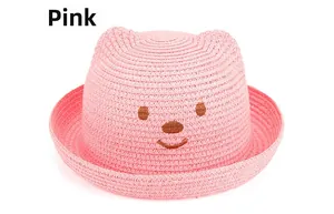 Détail d'un chapeau de soleil rose en paille tissée pour enfant avec oreilles d'ours mignon