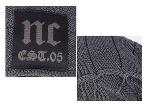 Macro detail of grey knitted beanie featuring a premium leather patch with embossed lettering