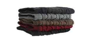 Detailed knit texture of five colorful winter beanies stacked on white background