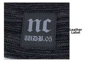 Macro detail of the dark gray knitted beanie featuring a black leather logo patch