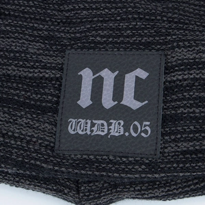Deep grey knitted beanie hat with a fleece lining and a square leather 'nc' logo patch