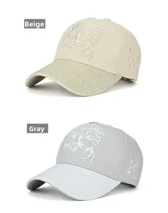Detail of cotton baseball caps in beige and grey featuring dragon embroidery and glitter brims