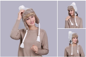Close-up of knit trapper hat with black snowflake patterns and white faux fur lining