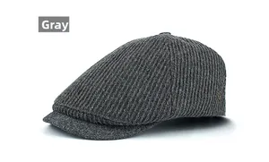 Detail view of dark grey winter flat cap with vertical ribbed wool texture and metal accent