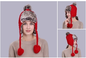 Detail of red cable-knit earflap hat with fluffy faux fur lining and plush pompom accents