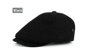Close-up of black corduroy newsboy cap with vertical textures and a gold metal emblem
