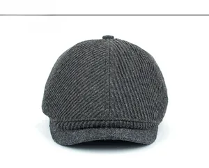 Front view showing the heavy wool blend tweed fabric and metal badge on a dark grey flat cap