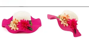 Detail of wide brim straw sun hat featuring vibrant pink wavy edges and floral accents