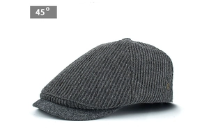 Detail of dark grey newsboy cap with vertical knit texture and golden logo pin
